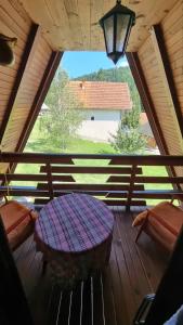 eine große Holzterrasse mit einem Tisch und einem Fenster in der Unterkunft Planinska Kuća Dušan in Mitrovac