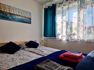 a bedroom with a bed and a window with blue curtains at Apartament Cicho Sza in Augustów