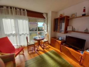 un soggiorno con tavolo e TV a schermo piatto di Coqueto apartamento a dos minutos de la playa a Somo