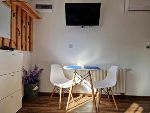 a table with four chairs and a tv on a wall at Apartament Cicho Sza in Augustów