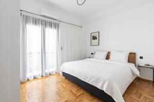 een witte slaapkamer met een bed en een groot raam bij Elliot in Athene