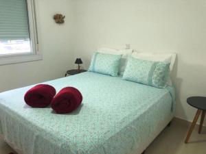 a bedroom with a bed with two red pillows on it at Buenos Aires 705 in Osório