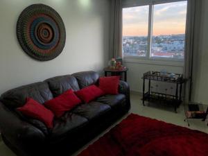 a living room with a black leather couch with red pillows at Buenos Aires 705 in Osório