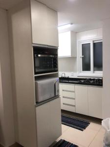 a kitchen with white cabinets and stainless steel appliances at Buenos Aires 705 in Osório