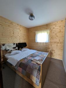 a bedroom with a bed with a wooden wall at Cabana Nyiko cu ciubăr in Lupeni
