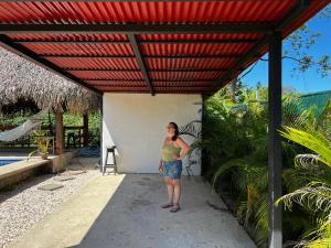 Uma mulher está debaixo de um telhado vermelho. em Las Plumas de Cabuya em Cabuya