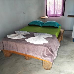 a bed with green sheets and pillows on it at Pensao Zé Doce in Portela