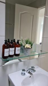 a bathroom sink with three bottles on a glass shelf at Aliaga Mar del Plata in Mar del Plata