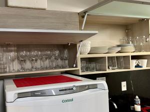 a kitchen with glasses and plates and a stove at Apartamento Maceió - De frente a Praia de Jatiuca in Maceió