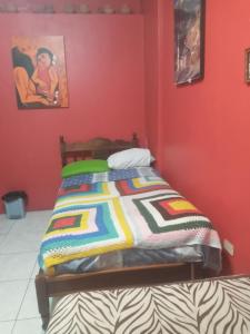 Bett in einem roten Zimmer mit einer bunten Decke in der Unterkunft Hostal-de don Pablo Del Centro Comercial in Quito