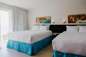 a hotel room with two beds and a window at Riotel Perce in Perce