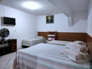 a bedroom with two beds and a flat screen tv at Pousada Guarulhos in Guarulhos