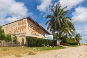 un edificio con una palmera al lado de un camino de tierra en Hotel Villaggio Tudo Bom, en Uruaú