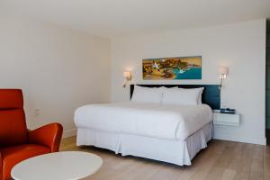 a hotel room with a white bed and a chair at Riotel Perce in Perce