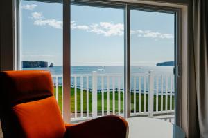 an orange chair sitting in front of a large window at Riotel Perce in Perce