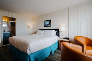 a hotel room with a large bed and a chair at Riotel Perce in Perce