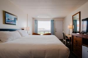 a hotel room with a bed and a desk and a television at Riotel Perce in Perce