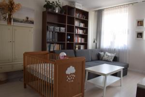 a baby crib in a living room with a couch at Blue Sky Apartment in Poznań