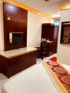 a hotel room with a tv and a bed and a desk at Dellagio Hotel in Wa