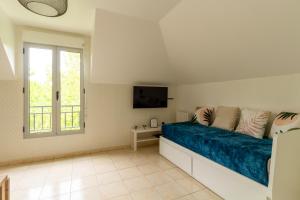 1 dormitorio con 1 cama con sábanas azules y TV en Le Bienvenue, en Bussy-Saint-Georges