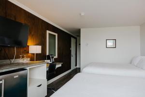 a bedroom with a bed and a desk with a tv at Riotel Perce in Perce