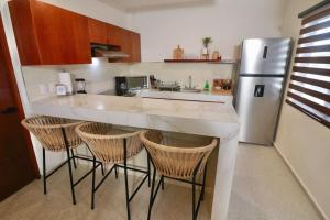 eine Küche mit einer Theke mit Stühlen und einem Kühlschrank in der Unterkunft Casa Belcher (Ray's) in Cozumel