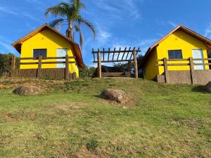 ein gelbes Haus auf einem Hügel mit einem Zaun in der Unterkunft Eco Chalés Pedra Bela in Pedra Bela