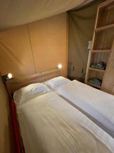 a bed in a room with two shelves at Safari Tent M in Berdorf