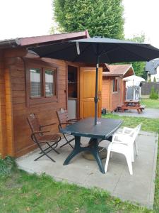 a picnic table with an umbrella in front of a cabin at Domki letniskowe Przyczepy kempingowe Zacisze Mielno in Mielno