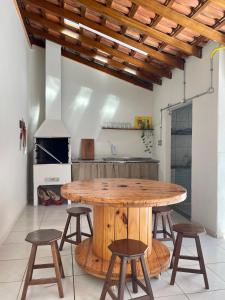 uma cozinha com uma mesa de madeira e alguns bancos em Casa Jabuticaba a 5 min dos Thermas e Hot Beach em Olímpia