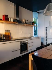 a kitchen with white cabinets and a table and a stove at Holland House Bay of Fires in Binalong Bay