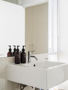a white bathroom with a sink and a mirror at Holland House Bay of Fires in Binalong Bay