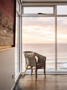 a wicker chair sitting in front of a large window at Holland House Bay of Fires in Binalong Bay