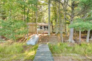 a house in the woods with a path leading to it at Serene Woodruff Cottage Lakefront Access! in Woodruff