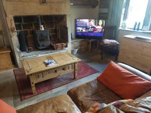 a living room with a couch and a fireplace with a tv at Charming 2-Bed Cottage in Hebden Bridge in Hebden Bridge
