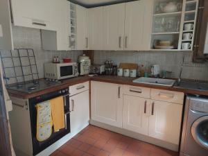 a kitchen with white cabinets and a stove top oven at Charming 2-Bed Cottage in Hebden Bridge in Hebden Bridge