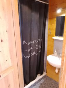 baño con cortina de ducha negra y lavamanos en Domki letniskowe Przyczepy kempingowe Zacisze Mielno, en Mielno