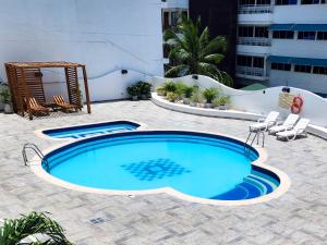 una piscina en un patio con sillas y un edificio en Apartamentos con vista al mar Brisa Marina Rodadero - by Bedviajes, en Santa Marta