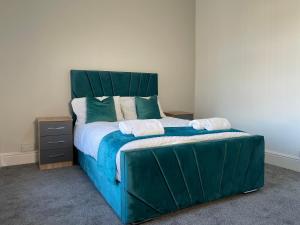 a bedroom with a large bed with a green headboard at Entire Modern Home Middlesbrough in Middlesbrough