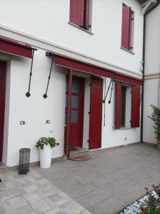 a white building with red doors and a patio at Casa della Magnolia in Conegliano