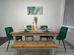 mesa de comedor con sillas verdes y mesa de madera con gafas en Entire Modern Home Middlesbrough, en Middlesbrough