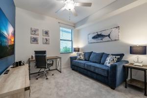 a living room with a blue couch and a desk at STUNNING New Construction Condo close to everything! - Condo Coastal Soul - Roelens Vacations in Fort Myers Villas