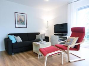 ein Wohnzimmer mit einem Sofa und einem roten Stuhl in der Unterkunft Strandoase - FeWo 21 in Bansin
