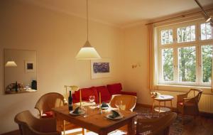 ein Wohnzimmer mit einem Tisch und einem roten Sofa in der Unterkunft Villa Daheim - FeWo 01 in Ostseebad Kölpinsee