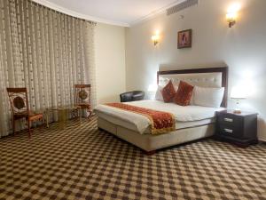 ein Hotelzimmer mit einem Bett und zwei Stühlen in der Unterkunft Abu Mazen Hotel in Khirbat an Naşārá