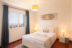 a bedroom with a white bed and a window at Pilar House in Funchal