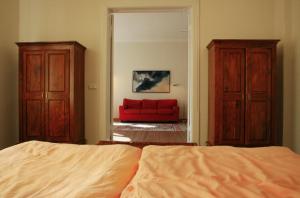 een slaapkamer met een bed en een rode bank bij Villa Daheim - FeWo 02 in Kolpinsee