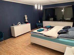 a bedroom with a large bed and a blue wall at Park Villa Ferienwohnung mit Pool und 3 Schlafzimmer in Uelzen