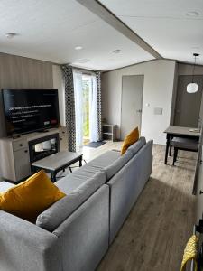 a living room with a couch and a flat screen tv at Fairway 6 Lilliardsedge Caravan Hire in Jedburgh