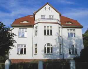 een wit huis met een rood dak bij Villa Daheim - FeWo 04 in Kolpinsee